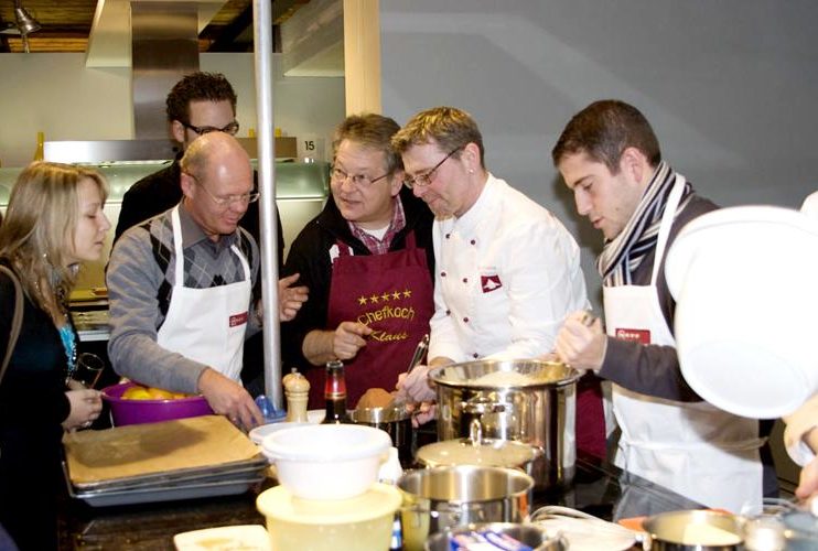 Teilnehmer des Kochkurses um eine Kücheninsel